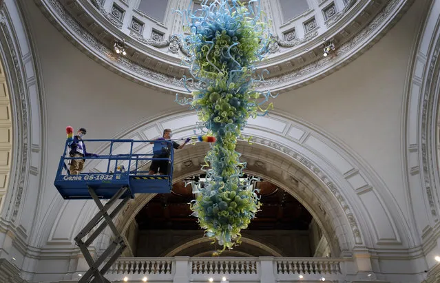 Museum technicians clean one of the V&A's most iconic and largest objects: a 27-foot glass chandelier made up of 1,300 exquisite blue and green glass elements, that hangs in the museum's Grand Entrance at the in London, Tuesday, August 4, 2020. The chandelier is the V&A Rotunda Chandelier by Dale Chihuly, 2001. On loan from Chihuly Studio, Seattle, Washington, USA. The museum will reopen to the public on Thursday Aug.6. (Photo by Kirsty Wigglesworth/AP Photo)