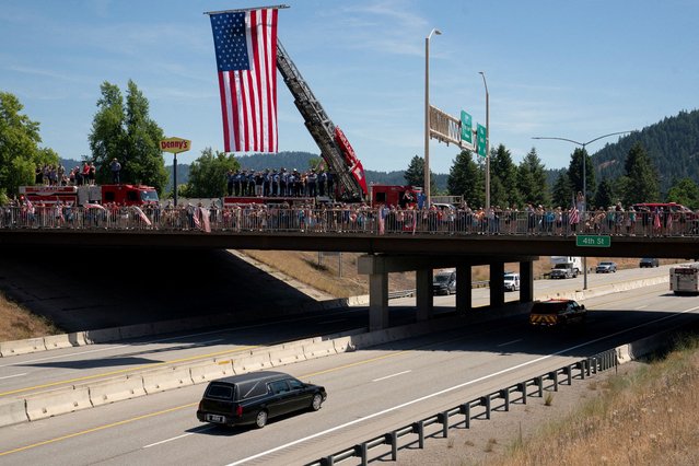 A hearse passes community members and firefighters, during a procession carrying the bodies of fallen firefighters John Morrison and Frank Harwood, who were shot dead while responding to a fire in the Canfield Mountain area outside Coeur d’Alene, Idaho on July 1, 2025. (Photo by David Ryder/Reuters)