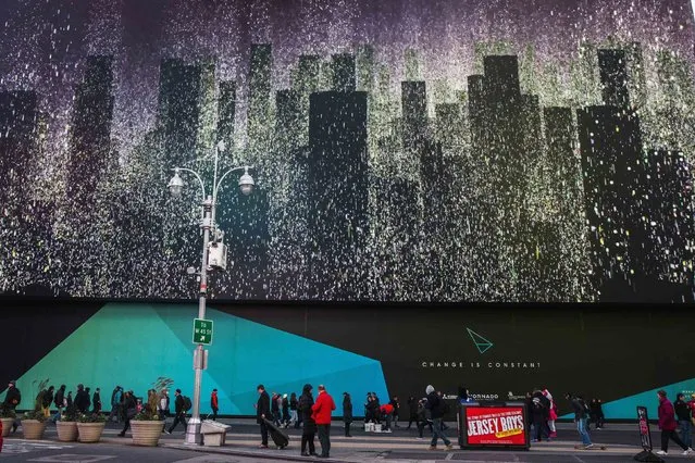 Pedestrians walk underneath a giant new advertising screen in Times Square, New York, November 19, 2014. (Photo by Carlo Allegri/Reuters)