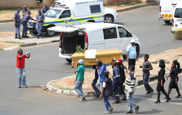 Police officers look on as striking funeral workers carry a coffin during a protest over changes to a host of procedures and regulations, during the coronavirus disease (COVID-19) outbreak, outside Chris Hani Baragwanath hospital, in Soweto, South Africa, September 16, 2020. (Photo by Siphiwe Sibeko/Reuters)