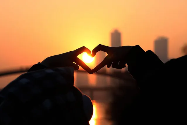 People make a heart shaped gesture as they look at the first sunrise of the year during New Year's celebrations at a park on January 1, 2023 in Seoul, South Korea. Seoul's New Years celebrations returns this year after it was cancelled during the Covid Pandemic. (Photo by Chung Sung-Jun/Getty Images)