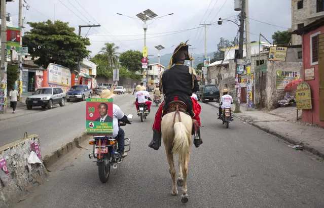 In this October 17, 2015 photo, a man dressed as independence hero Jean Jacques Dessalines rides a horse alongside fellow campaigners on motorcycles as they promote presidential candidate Moise Jean Charles, of the Platform Pitit Dessalines political party, in Port-au-Prince, Haiti. (Photo by Dieu Nalio Chery/AP Photo)