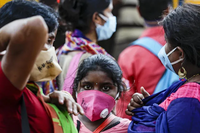 A family wearing face masks to prevent the spread of the coronavirus wait for a bus in Kolkata, India, Friday, October 30, 2020. Health officials have warned about the potential for the coronavirus to spread during the upcoming religious festival season, which is marked by huge gatherings in temples and shopping districts. (Photo by Bikas Das/AP Photo)