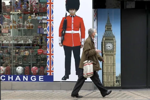 A person wearing a face mask walks past a temporarily closed souvenir store on Oxford Street, during England's second coronavirus lockdown, in London, Monday, November 23, 2020. British Prime Minister Boris Johnson has announced plans for strict regional measures to combat COVID-19 after England's second lockdown ends Dec. 2, sparking a rebellion by members of his own party who say the move may do more harm than good. (Photo by Matt Dunham/AP Photo)