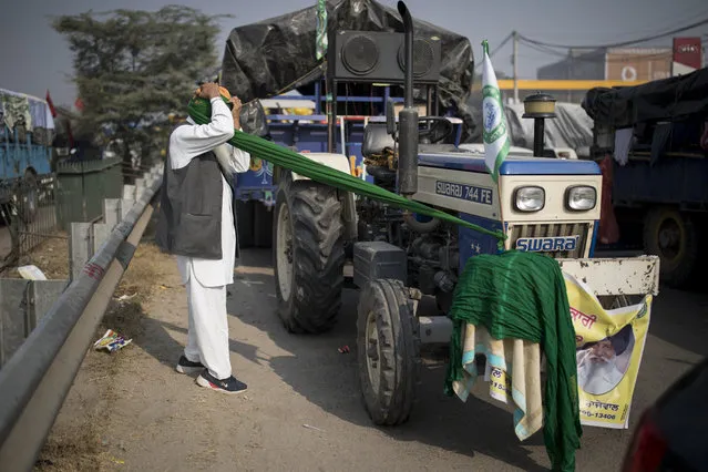 Jagir Singh, 71, ties his turban before joining fellow farmers for a protest against new farm laws, at the Delhi-Haryana state border, India, Tuesday, December 1, 2020. The farmers have laid a siege of sorts on the highway, sleeping inside the trailers or under the trucks at night. During the day, they sit huddled in groups at the backs of the vehicles, surrounded by mounds of rice, lentils and vegetables. They say they are not going to leave the place until their demands are met. (Photo by Altaf Qadri/AP Photo) 