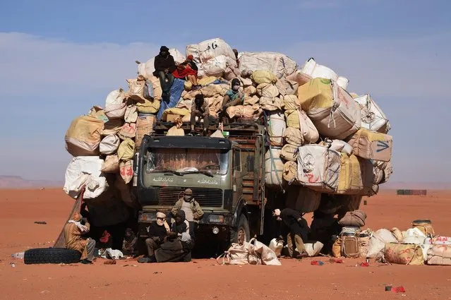 People sit near a fully loaded in Madama near the border with Lybia on January 1, 2015. French Defence Minister Jean-Yves Le Drian paid a surprise visit to northern Niger on January 1, to visit a base being built to combat the growing flow of weapons and jihadists from neighbouring Libya. Le Drian travelled from Chad to Madama, a desert outpost about 100 kilometres from Libya, where he saw in the New Year with troops at a French base. (Photo by Dominique Faget/AFP Photo)