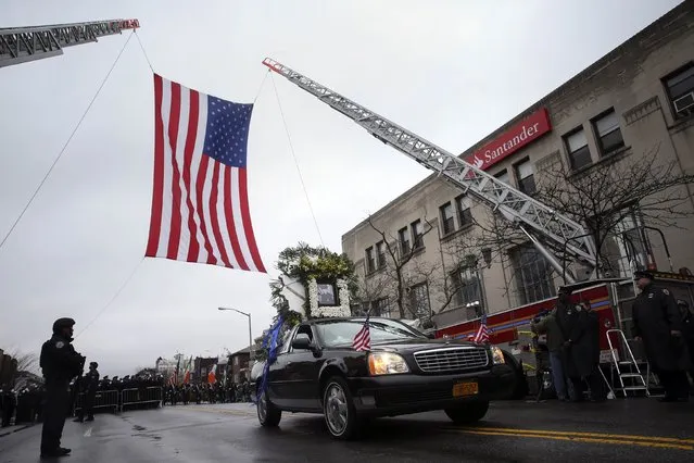 The lead funeral procession vehicle for NYPD officer Wenjian Liu makes its way under a US flag en route to the cemetery in the Brooklyn borough of New York January 4, 2015. (Photo by Shannon Stapleton/Reuters)