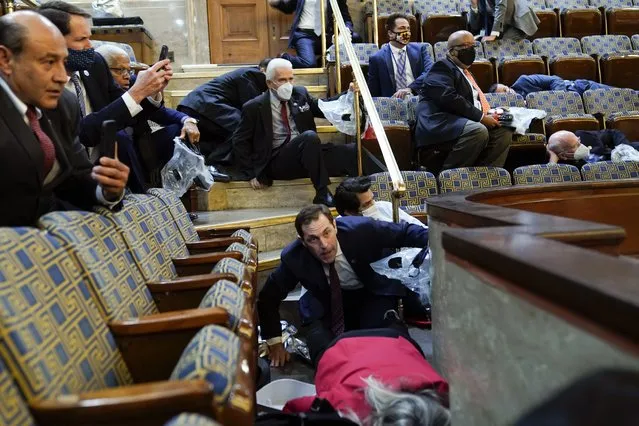 People shelter in the House gallery as protesters try to break into the House Chamber at the U.S. Capitol on Wednesday, January 6, 2021, in Washington. (Photo by Andrew Harnik/AP Photo)