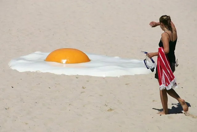 A woman approaches an artwork called “Big Chook”, made of fibreglass and high gloss epoxy marine paint, on Tamarama Beach in Sydney November 2, 2005. Australian artist Jeremy Parnell says people frying themselves on the beach for a suntan inspired his piece which joins 100 artworks contributed by international and Australian artists at the annual outdoor Sculpture by the Sea exhibition which is in its ninth year. (Photo by Will Burgess/Reuters)