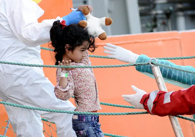 A child is helped to disembark from the Norwegian vessel Siem Pilot in the Sicilian harbour of Palermo, Italy, October 24, 2016. (Photo by Guglielmo Mangiapane/Reuters)