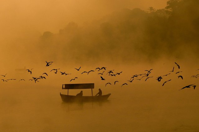 Men row a boat amidst dense fog across the Narmada river during a winter morning, in Jabalpur, India on November 11, 2025. (Photo by Uma Shankar Mishra/AFP Photo)