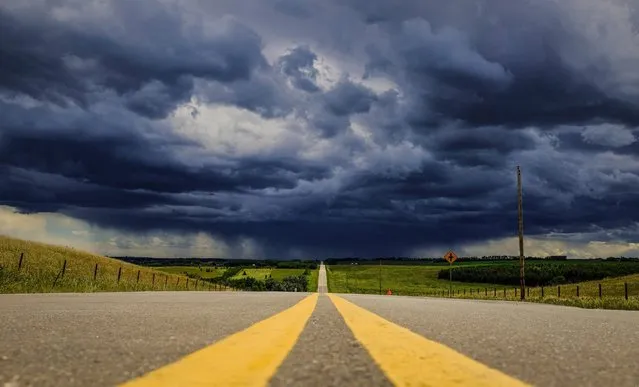 Storm clouds build over a highway in southern Alberta near the town of Carstairs, Canada, Monday, July 4, 2016. Southern and central Alberta have been seeing numerous storm warnings and a few tornado warnings in the last few days as severe thunderstorms capable of producing strong wind gusts, large hail and heavy rain pass through the region. (Photo by Jeff McIntosh/The Canadian Press via AP Photo)
