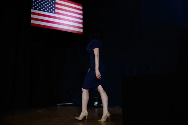 An aide for President Donald Trump, with her face in shadow with her dark hair, walks off stage after bringing his speech to the podium at the “Salute to Service” dinner, Tuesday, July 3, 2018, in White Sulphur Springs, W.Va. (Photo by Evan Vucci/AP Photo)