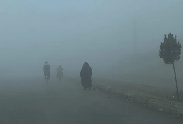An Afghan woman with Burqa, right walks during a heavy fog in Kabul, Afghanistan, Tuesday, February 23, 2021. (Photo by Rahmat Gul/AP Photo)
