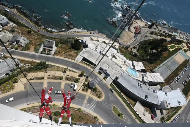 Workers wave as they clean the windows of a building dressed of Santa Claus in Vina del Mar city, Chile December 23, 2015. (Photo by Rodrigo Garrido/Reuters)