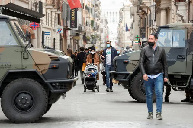 People walk past army vehicles at a street on the final day of open restaurants and bars before tighter coronavirus disease (COVID-19) restrictions are enforced, in Rome, Italy, March 14, 2021. (Photo by Remo Casilli/Reuters)