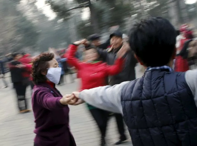 A woman wearing a protective mask dances in a park as China's capital Beijing braces for four days of choking smog starting Saturday, in Beijing, China, December 19, 2015. (Photo by Kim Kyung-Hoon/Reuters)