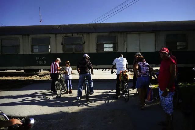 In this July 25, 2018 photo, residents wait for the train to move so they can cross the track in Guantanamo, Cuba, near the U.S. Guantanamo Bay naval base. The “El Guantanamero” train connects Guantanamo with the capital city of Havana, and is used to transport passengers as well as cargo. (Photo by Ramon Espinosa/AP Photo)
