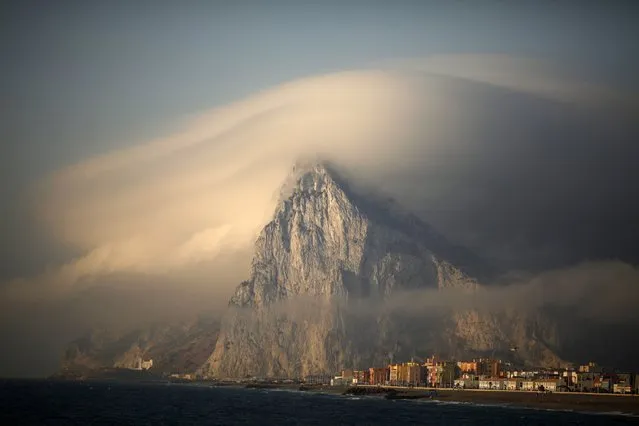 A cloud partially covers the tip of the Rock of the British territory of Gibraltar at sunrise from La Atunara port before Spanish fishermen sail in their fishing boats with their relatives to take part in a protest at an area of the sea where an artificial reef was built by Gibraltar using concrete blocks, in Algeciras bay, La Linea de la Concepcion in southern Spain August 18, 2013. (Photo by Jon Nazca/Reuters)