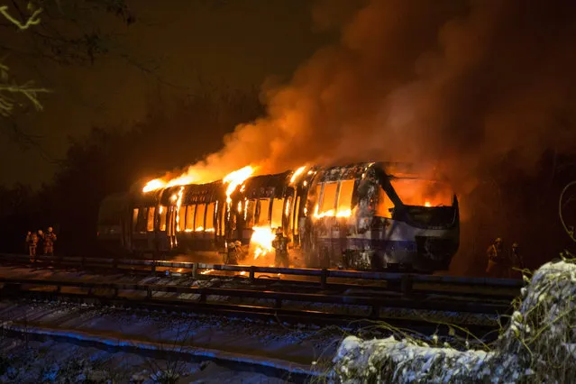 Firefighters stand in front of a burning regional train in Berlin-Hellersdorf, Germany, 06 January 2016. Some 180 passengers were able to leave the train unharmed. (Photo by Christopher Harms/EPA)