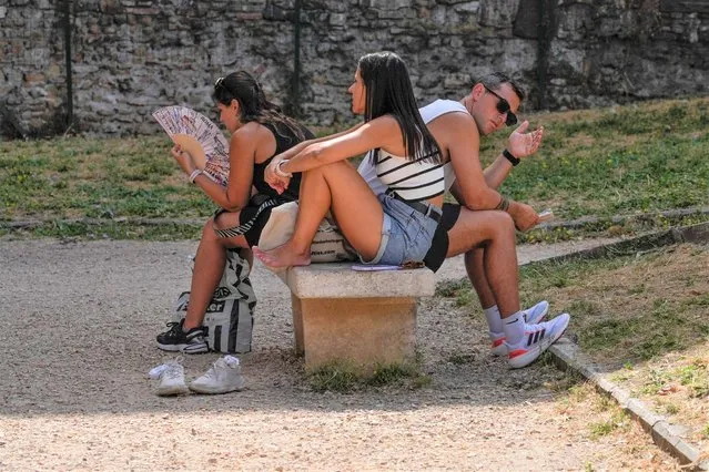 Tourists rest on a bench in Rome, Monday, July 17, 2023. Tourist flock to the eternal city while scorching temperatures grip central Italy with Rome at the top of the red alert list as one of the hottest cities in the country. (Photo by Gregorio Borgia/AP Photo)