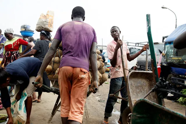 A labourer pushes a wheelbarrow containing tuber through a local foodstuff market in Lagos,Nigeria November 2, 2016. (Photo by Akintunde Akinleye/Reuters)