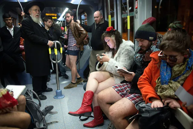 People taking part in the annual international "No Pants Subway Ride" day travel on the Jerusalem light train on January 10, 2016. The "no pants" day is now marked in over 60 cities around the world. The idea behind it is that random passengers board a subway car at separate stops in the middle of winter, without wearing trousers. The participants wear all of the usual winter clothing on their top half such as hats, scarves and gloves and do not acknowledge each other's similar state of undress. (Photo by Menahem Kahana/AFP Photo)