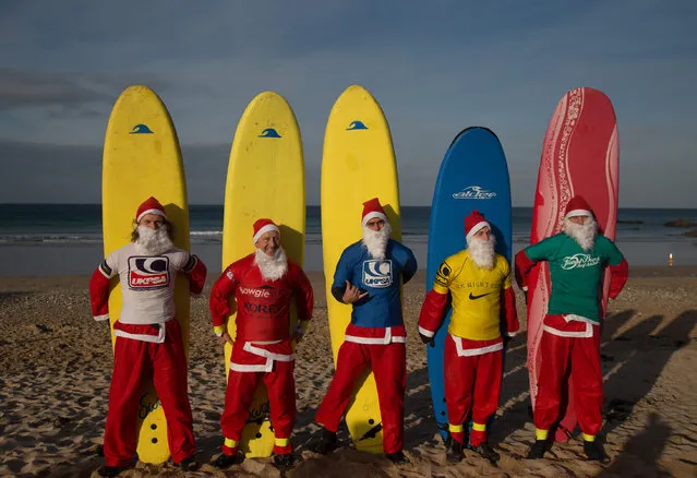 Surfers dressed as Santa pose for a photograph before competing in a heat during the annual Surfing Santa as part of the Santa Run and Surf 2016 at Fistral Beach in Newquay on December 4, 2016 in Cornwall, England. Now in its third year, the santa surf and fun run is organised by Fistral Surf Center and Cornwall Hospice Care and raises funds for local charities. (Photo by Matt Cardy/Getty Images)