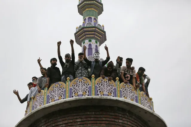 Kashmiri villagers shout slogans on top of a mosque which was partially damaged during a gunbattle at Panzan, about 35 kilometers south of Srinagar, Indian controlled Kashmir, Thursday, September 27, 2018. At least two militants were trapped in a mosque after troops laid a siege around it in the village, police said. As the siege continued, villagers tried to march towards the mosque in solidarity with the rebels, leading to clashes between stone-throwing protesters and government forces who deployed tear smoke shells and pellets. (Photo by Mukhtar Khan/AP Photo)