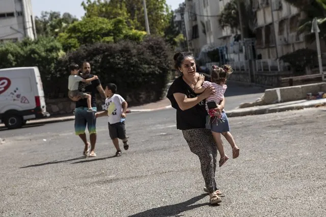 Lia Tal, 40, rushes with her children and partner to take shelter as a siren sounds a warning of incoming rockets fired from the Gaza Strip, In Ashdod, Israel, Thursday, May 20, 2021. (Photo by Heidi Levine/AP Photo)