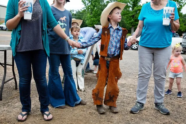 Lincoln Patton, 6, holds hands with his mother Janine Patton and grandmother Janet Winebark as they wait in line for food at the Lindale Championship Rodeo in Lindale, Texas, May 15, 2021. (Photo by Shelby Tauber/Reuters)
