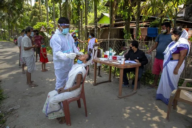 An Indian health worker in protective suit takes the swab of a village woman to test for COVID-19 in Burha Mayong village, Morigaon district of Assam, India, Saturday, May 22, 2021. (Photo by Anupam Nath/AP Photo)