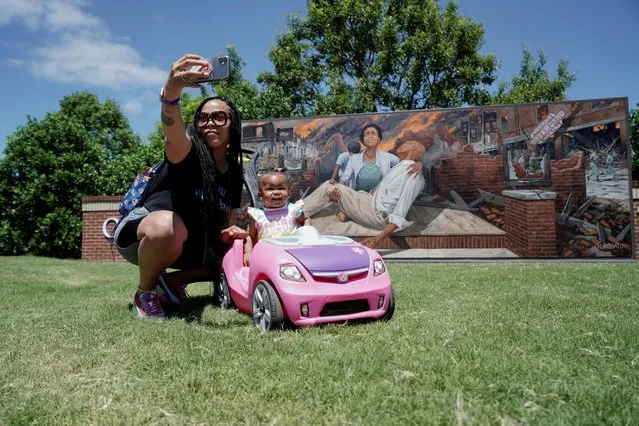 A mother and a child take a photo in front of a mural ahead of the 100th anniversary of the 1921 Tulsa Massacre in Tulsa, Oklahoma, U.S., May 29, 2021. (Photo by Lawrence Bryant/Reuters)