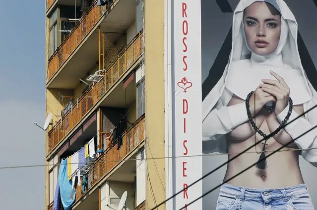 A huge poster shows a model wearing jeans and part of a nun's habit, on a building in Naples March 11, 2015. Rosso di Sera, an Italian ready-to-wear clothing chain, has caused a stir by putting up the huge publicity poster of a semi-nude woman dressed as a nun in Naples less than two weeks before Pope Francis is due to visit the southern port city. (Photo by Ciro De Luca/Reuters)