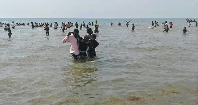 People help a man to come ashore from Lake Albert, on December 26, 2016 in Buliisa, after at least 30 Ugandan members of a village football team and their fans drowned when their boat capsized on Lake Albert during a party. (Photo by AFP Photo)