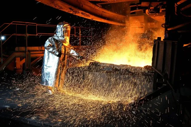 A worker in a protective suit pokes a metal rod to tap slag from a smelting furnace at PT Vale Indonesia's nickel processing plant in Sorowako, South Sulawesi, Indonesia, Tuesday, September 12, 2023. As demand for materials needed for batteries, solar panels and other components vital for cutting global emissions rises, carbon emissions by miners and refiners will likewise rise unless companies actively work to decarbonize. (Photo by Dita Alangkara/AP Photo)