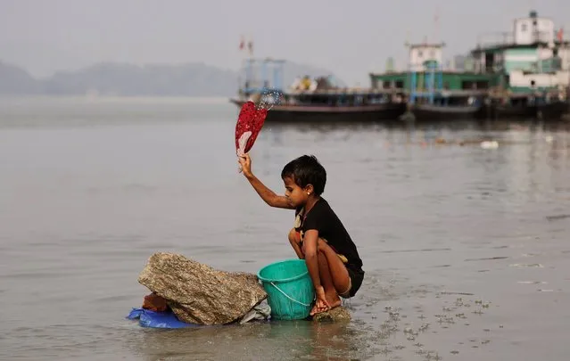 An Indian girl washes clothes in the River Brahmaputra in Gauhati, India, Thursday, December 12, 2013. Dhobis are traditional laundry workers who wash clothes by hand and dry them in the sun, an occupation which has been in existence for generations with a current earning of 65- 81 US cents per cloth. (Photo by Anupam Nath/AP Photo)