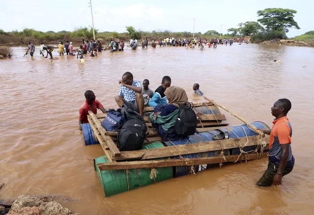 People cross a flooded area on makeshift floating tanks at Mororo, border of Tana River and Garissa counties, North Eastern Kenya, Thursday, November 30, 2023. Kenya's government is urging people living in flood-prone areas to relocate to higher ground as heavy rains and flash floods continued to wreak havoc across East Africa. (Photo by AP Photo)