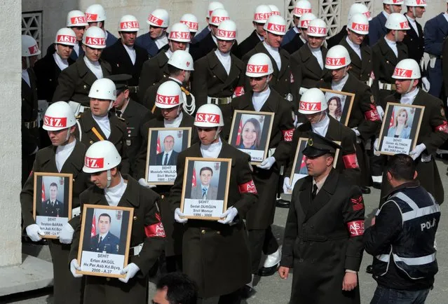 Soldiers carry the portraits of victims during funeral prayers for eight of the 28 victims of Wednesday's explosion in Ankara, Turkey, Friday, February 19, 2016. Turkish authorities on Friday detained three more suspects in connection with the deadly bombing in Ankara that Turkey has blamed on Kurdish militants at home and in neighboring Syria, while Turkey's military pushed ahead with its cross-border artillery shelling campaign against U.S.-backed Syrian Kurdish militia positions in Syria. (Photo by Burhan Ozbilici/AP Photo)