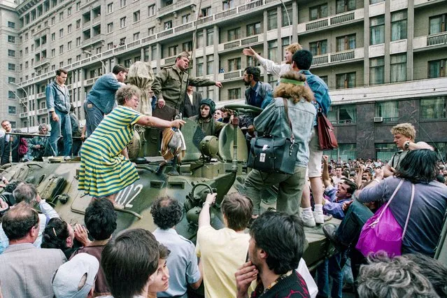 In this Monday, August 19, 1991 file photo, a crowd gathers around a personnel carrier as some people climb aboard the vehicle and try to block its advance near Red Square in downtown Moscow, Russia. (Photo by Boris Yurchenko/AP Photo/File)