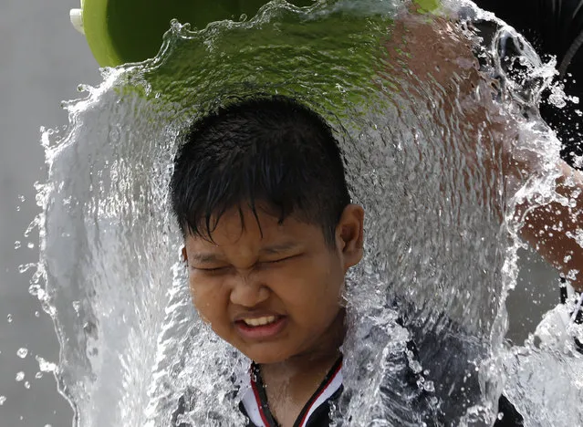 A boy reacts as a bucket of water is splashed on him during the Songkran water festival to celebrate Thai New Year in Bangkok, Thailand, Monday, April 13, 2015. (Photo by Sakchai Lalit/AP Photo)