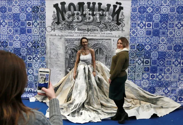 A visitor poses for a picture with Russian artist Maria Gasanova, who presents a body art creation, part of her “Alive Painting” project, during a fashion exhibition in the Siberian city of Krasnoyarsk, Russia on January 31, 2019. (Photo by Ilya Naymushin/Reuters)