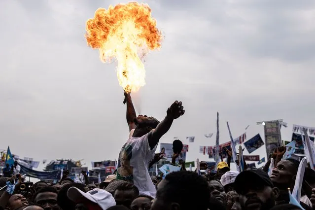 A supporter of President of the Democratic Republic of the Congo (DRC) and leader of the Union of Democracy and Social Progress (UDPS) party, Felix Tshisekedi, and blows fire at a campaign rally at Sainte Therese in the Ndjili district of Kinshasa on December 18, 2023. Forty-four million people are registered to vote in the presidential, parliamentary, provincial and municipal elections scheduled for December 20, 2023 in the central African nation of about 100 million people. (Photo by John Wessels/AFP Photo)