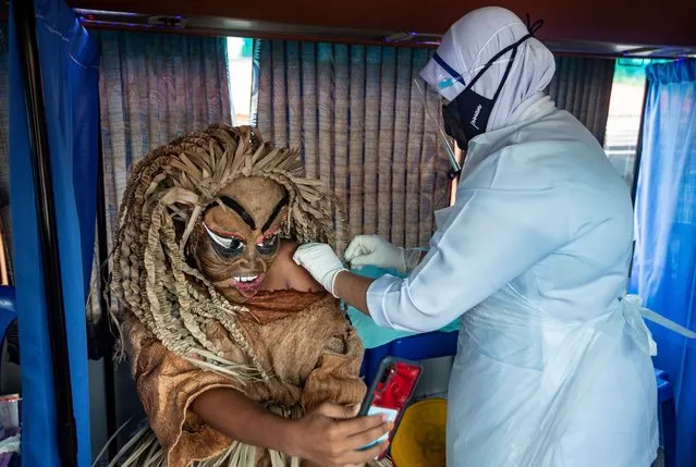 An indigenous man of Mahmeri tribe wearing a costume of Puteri Gunung Ledang character receives a dose of the vaccine against Covid-19 in Banting, near Kuala Lumpur, Malaysia,15 August 2021. Malaysia recorded another 20,670 new Covid-19 cases on 14 August, bringing the cumulative total to 1,384,353 cases. (Photo by Ahmad Yusni/EPA/EFE)