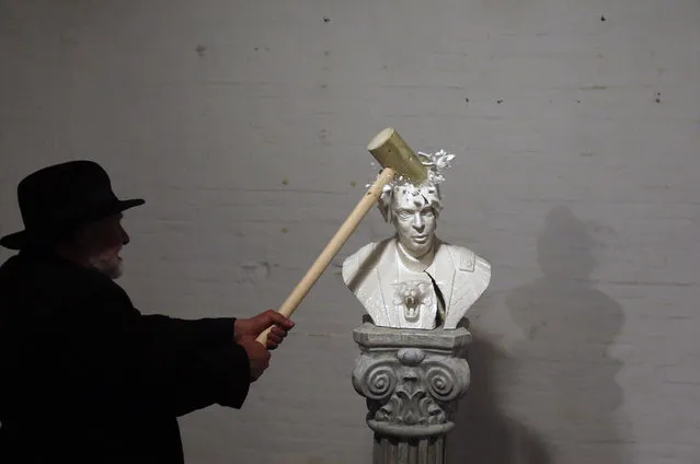 Serbian artist Zivko Grozdanic smashes a statue of Prime Minister Aleksandar Vucic, during a photocall, in the village of Veliko Srediste, Serbia, on April 22, 2016. The populist leader has ruled the Balkan nation for more than a decade as both prime minister and president. After his populists won a weekend snap parliamentary election, Vucic seems set to tighten his already autocratic rule still further. (Photo by Darko Vojinovic/AP Photo)
