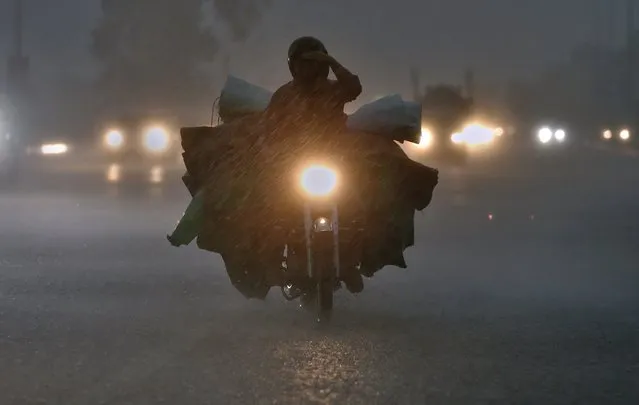 A motorcyclist and other vehicles drive with headlights during a heavy rainfall in Islamabad, Pakistan, Monday, September 20, 2021. (Photo by Anjum Naveed/AP Photo)
