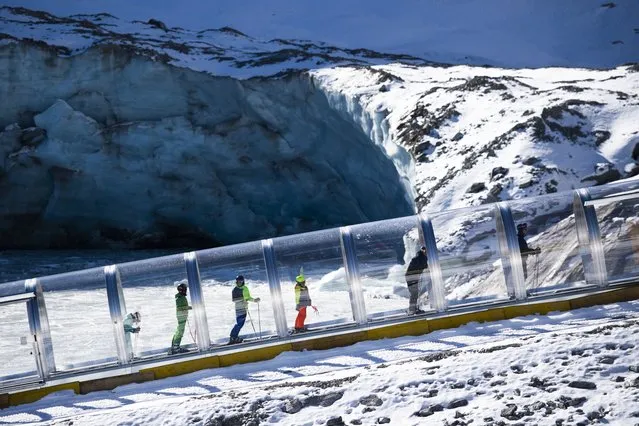Tourists use a conveyer belt to get to the slopes, pictured prior the FIS Alpine Ski World Cup season in Soelden, Austria, 22 October 2021. The Alpine Skiing World Cup season 2021/22 will be opened this weekend in Soelden, the traditional start of the FIS Ski World Cup. (Photo by Gian Ehrenzeller/EPA/EFE)