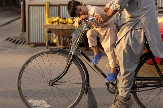A boy sleeps as he rides a bicycle in Kabul, Afghanistan on October 18, 2021. (Photo by Jorge Silva/Reuters)