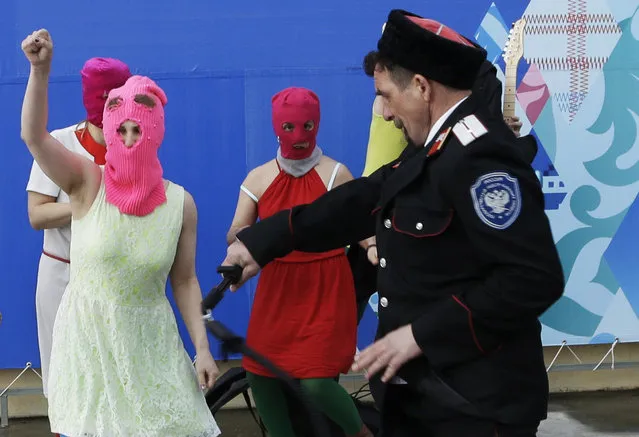 Members of the punk group p*ssy Riot, including Nadezhda Tolokonnikova in the blue balaclava and Maria Alekhina in the pink balaclava, are attacked by Cossack militia in Sochi, Russia, on Wednesday, February 19, 2014. (Photo by Morry Gash/AP Photo)