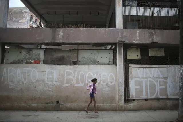 A child plays in front of a wall that reads “Down with the blockade, long live Fidel”, in downtown Havana, Cuba March 21, 2016. (Photo by Alexandre Meneghini/Reuters)